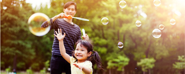 Father and daughter play with bubbles.