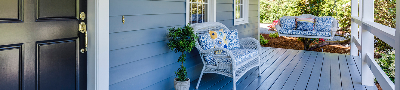 A porch painted blue with white wicker furniture.